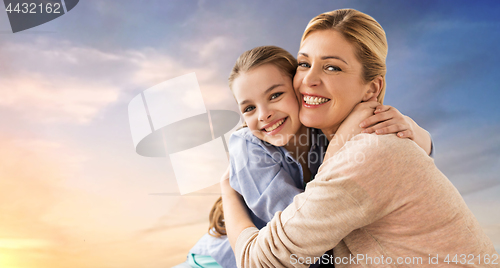 Image of happy smiling mother hugging daughter over sky
