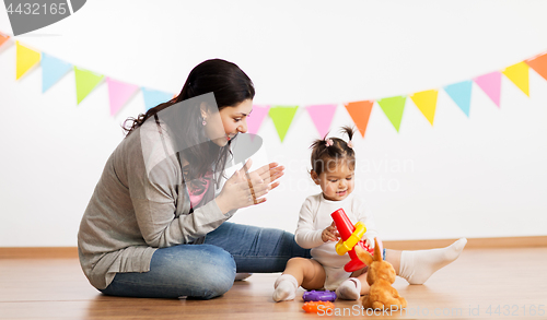 Image of mother and baby daughter playing with pyramid toy