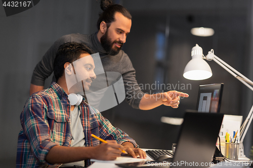 Image of creative team with computer working late at office