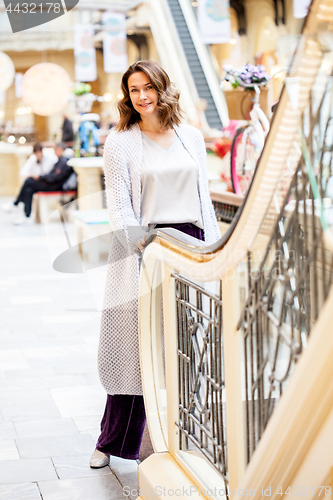 Image of woman in a blue knitted coat near an escalator in a shopping cen