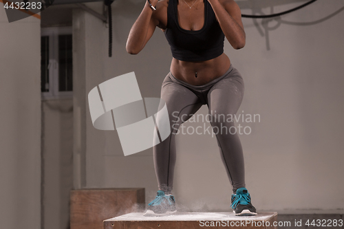 Image of black woman is performing box jumps at gym