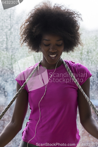 Image of portrait of young afro american woman in gym while listening mus