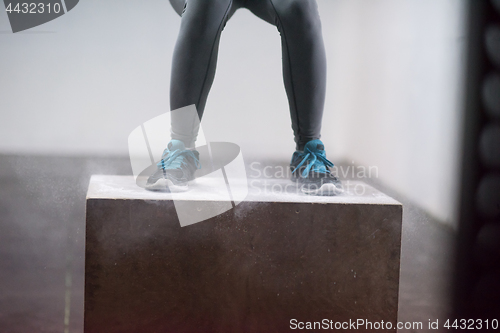 Image of black woman is performing box jumps at gym