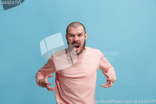 Image of The young emotional angry man screaming on blue studio background