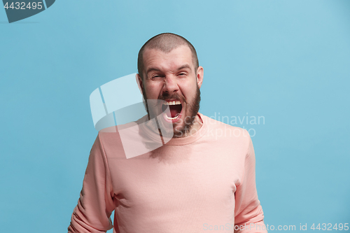 Image of The young emotional angry man screaming on blue studio background