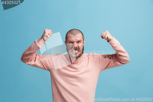 Image of The young emotional angry man screaming on blue studio background