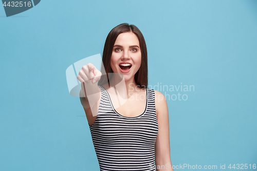 Image of The happy woman point you and want you, half length closeup portrait on blue background.