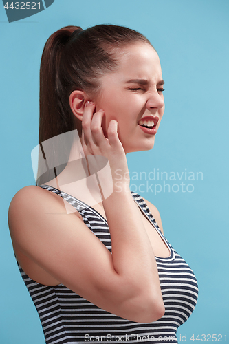 Image of The Ear ache. The sad woman with headache or pain on a blue studio background.