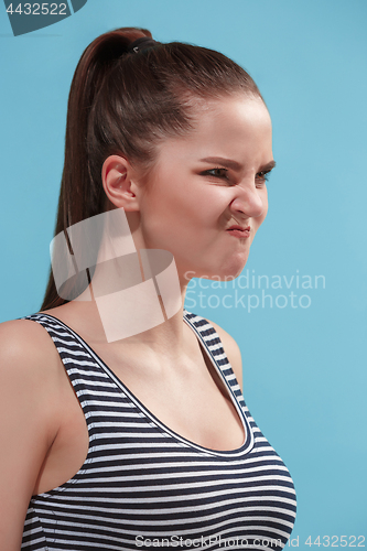 Image of The young woman is looking angry on the blue background.