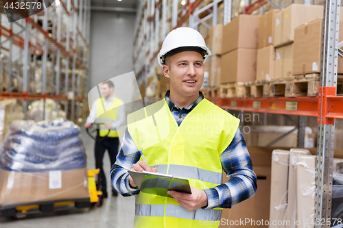 Image of warehouse worker with clipboard in safety vest