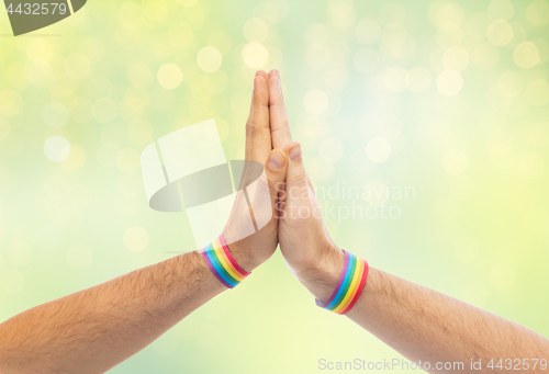 Image of hands with gay pride wristbands make high five