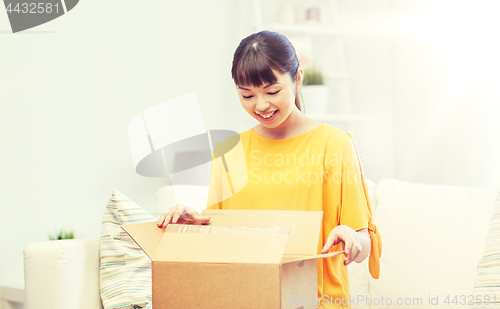 Image of happy asian young woman with parcel box at home
