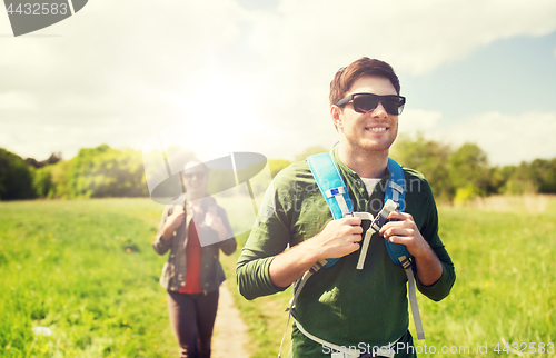 Image of happy couple with backpacks hiking outdoors