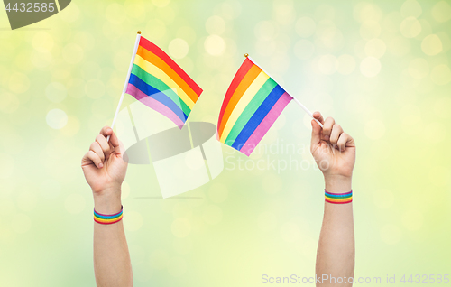 Image of hand with gay pride rainbow flags and wristbands