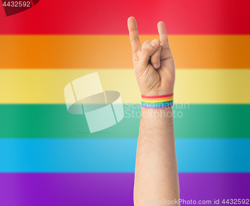 Image of hand with gay pride rainbow wristband shows rock