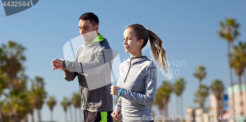 Image of couple with fitness trackers running outdoors