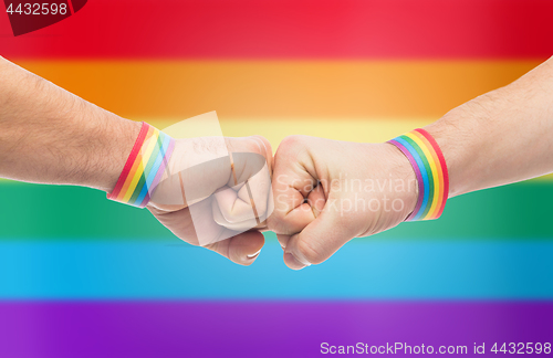 Image of hands with gay pride wristbands make fist bump