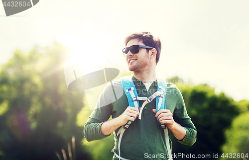 Image of happy young man with backpack hiking outdoors