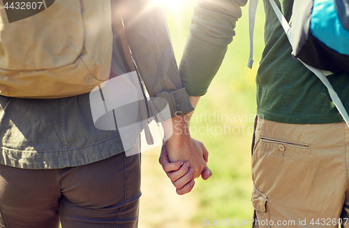 Image of close up of couple with backpacks holding hands