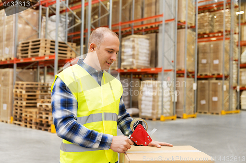 Image of warehouse worker packing parcel with scotch tape