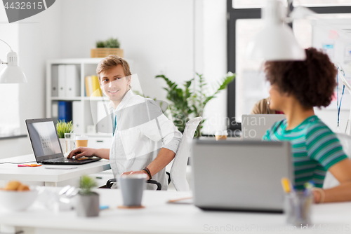 Image of happy creative workers with laptops at office