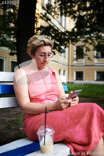 Image of Adult woman using smartphone on bench