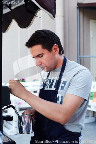 Image of Barista pouring milk in cup