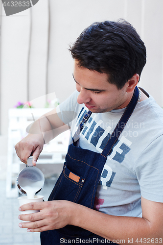 Image of Barista pouring milk in cup