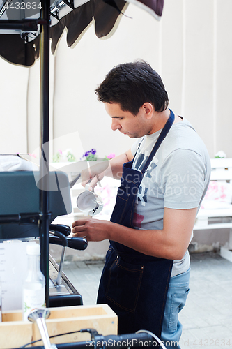 Image of Barista pouring milk in cup