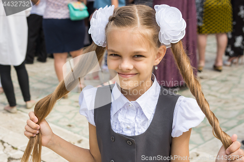 Image of Schoolgirl at the festival on September 1 holds her long hair in her hands