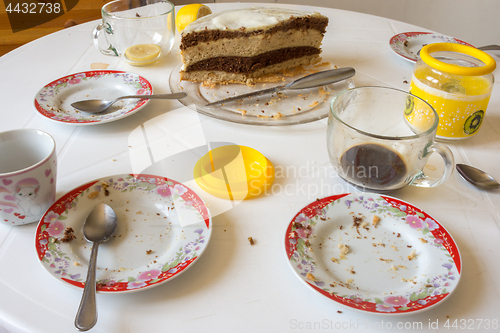 Image of Dirty dishes on the table, homemade cake in the background