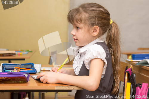 Image of A girl first-graders attentively listens to the teacher at school