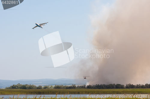Image of Extinguishing fire from the air using an airplane and a helicopter, with the burning of reeds on the floodplains of the Anapka River, Anapa, Russia