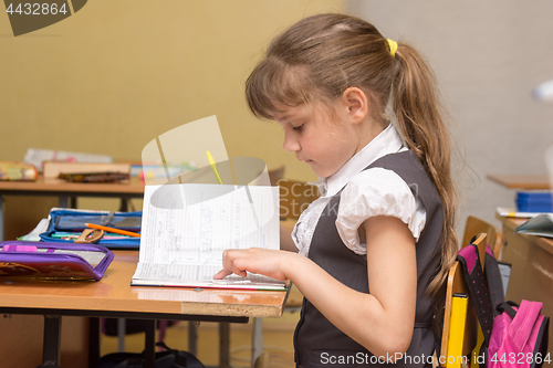 Image of A little girl in a class carefully reads a diary entry