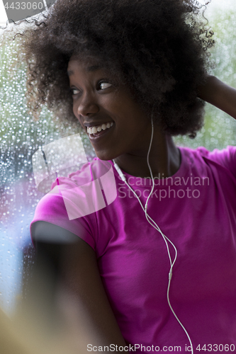 Image of portrait of young afro american woman in gym while listening mus