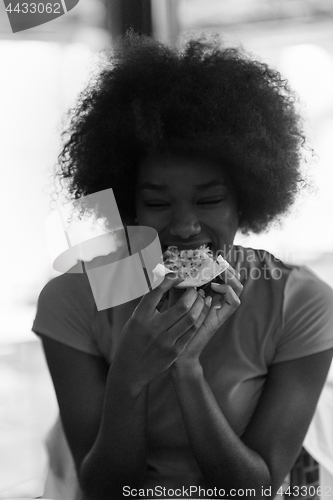 Image of woman with afro hairstyle eating tasty pizza slice