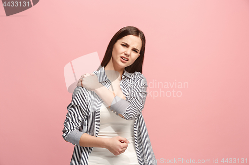 Image of The shoulder ache. The sad woman with shoulder ache or pain on a pink studio background.