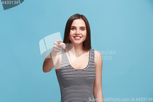 Image of The happy woman point you and want you, half length closeup portrait on blue background.