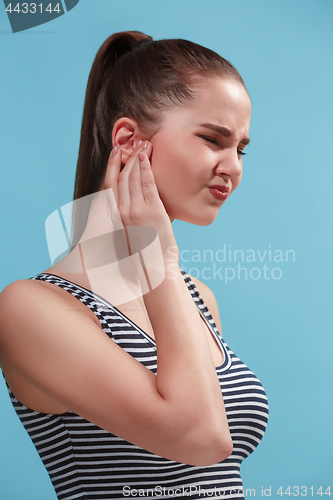 Image of The Ear ache. The sad woman with headache or pain on a blue studio background.