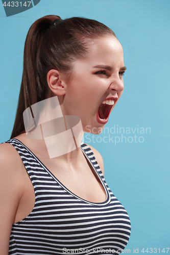 Image of The young woman is looking angry on the blue background.