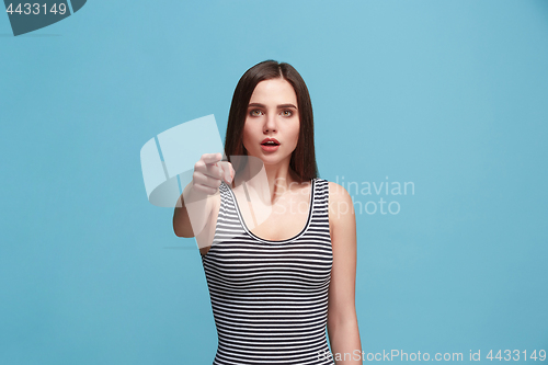 Image of The woman point you and want you, half length closeup portrait on blue background.