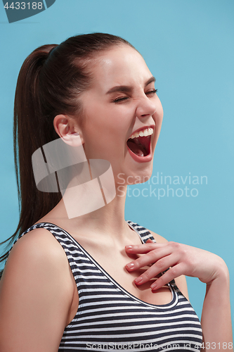 Image of The happy woman standing and smiling against blue background.