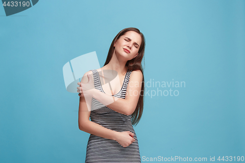 Image of The shoulder ache. The sad woman with shoulder ache or pain on a blue studio background.