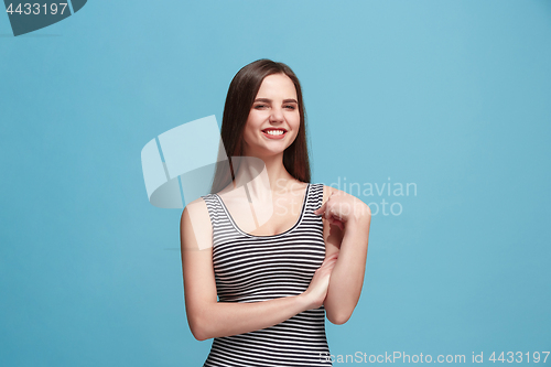 Image of The happy woman standing and smiling against blue background.