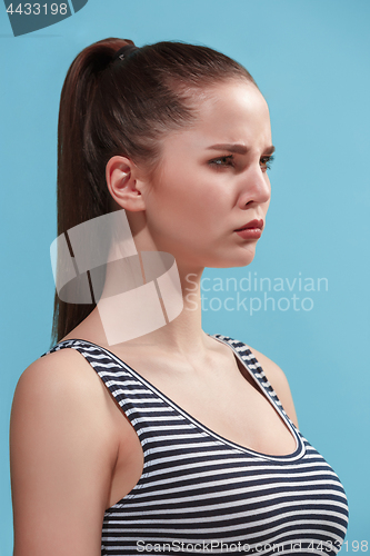 Image of The young woman is looking angry on the blue background.