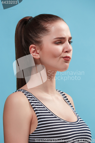 Image of The young woman is looking boring on the blue background.