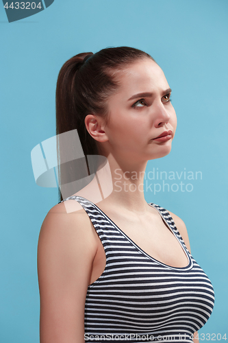 Image of The young woman is looking boring on the blue background.