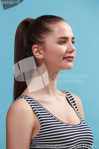 Image of The happy woman standing and smiling against blue background.