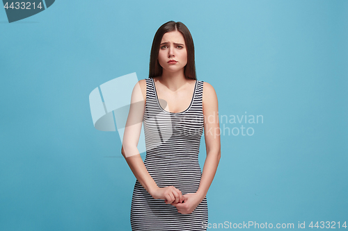 Image of The awkward woman standing and looking at camera against blue background.