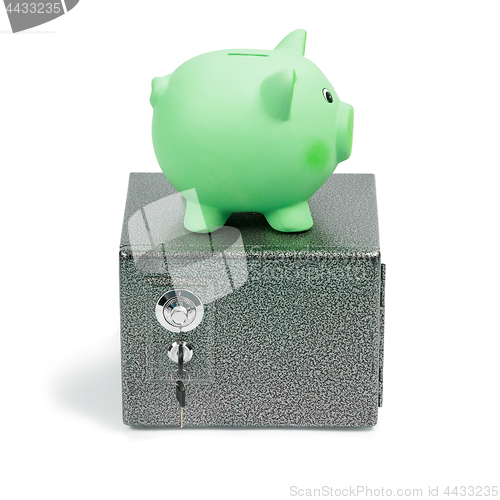 Image of Green ceramic piggy bank standing on a safe